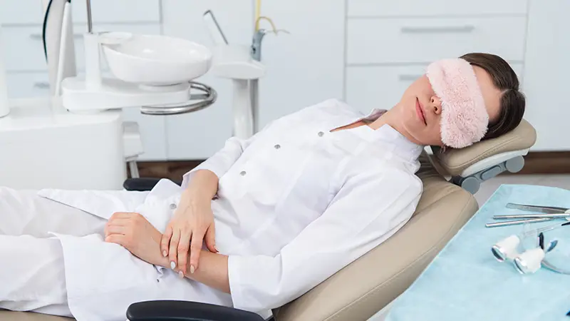 Woman resting on a dental chair with a sleeping mask